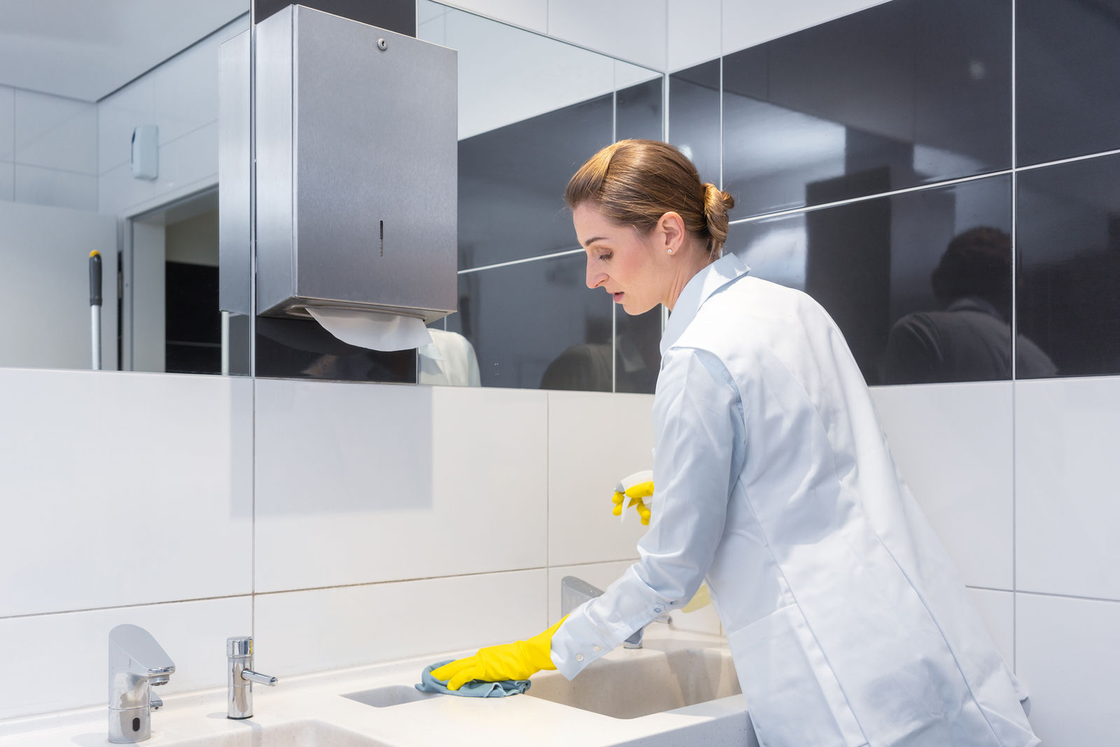 Sanitärreinigung im Büro: Waschbecken und Armaturen werden gereinigt